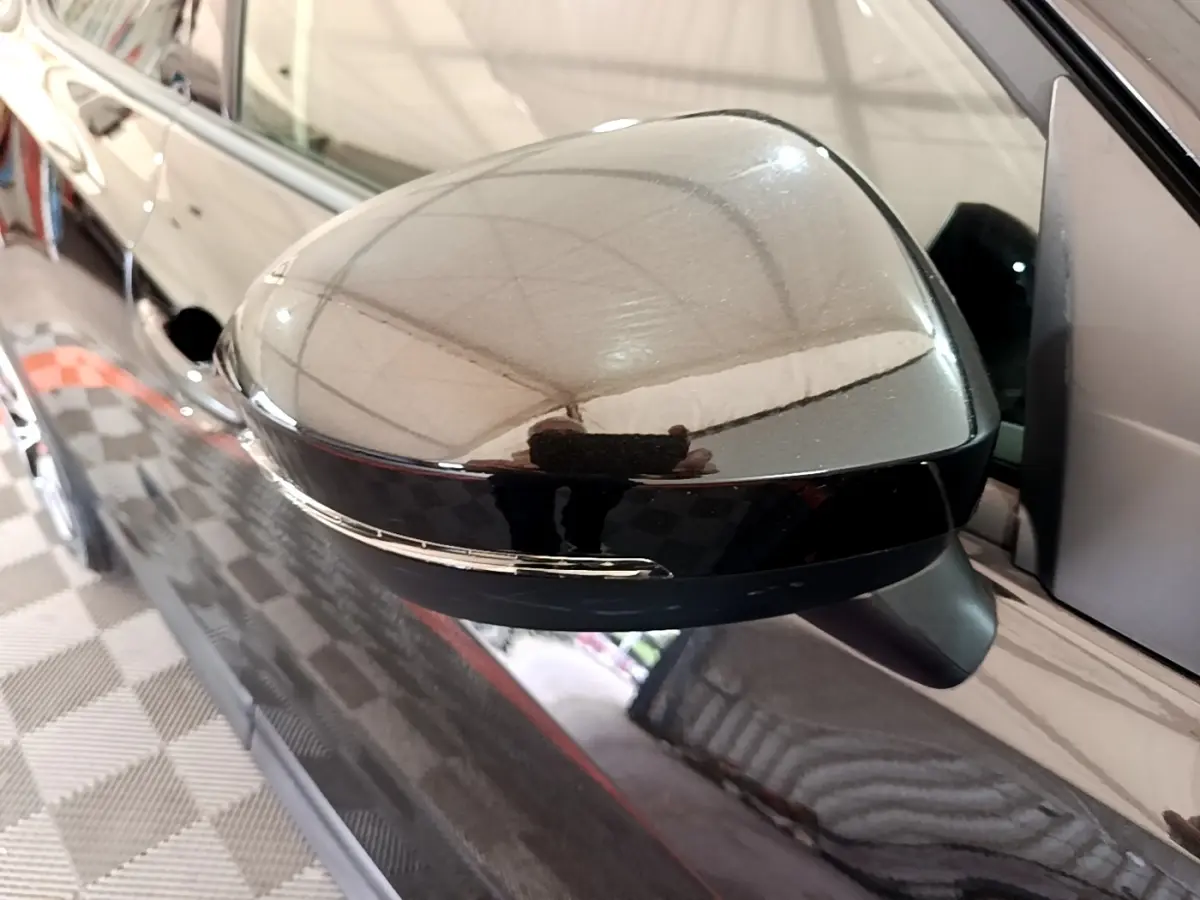 Rétroviseur extérieur noir côté conducteur du Nissan Juke 2023 avec clignotant intégré, vue rapprochée en intérieur.