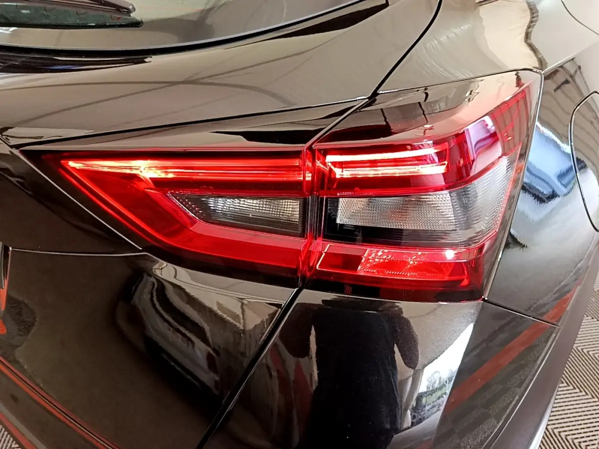 Gros plan sur le feu arrière droit rouge d’un Nissan Juke noir 2023, mettant en valeur ses lignes anguleuses et détails lumineux.