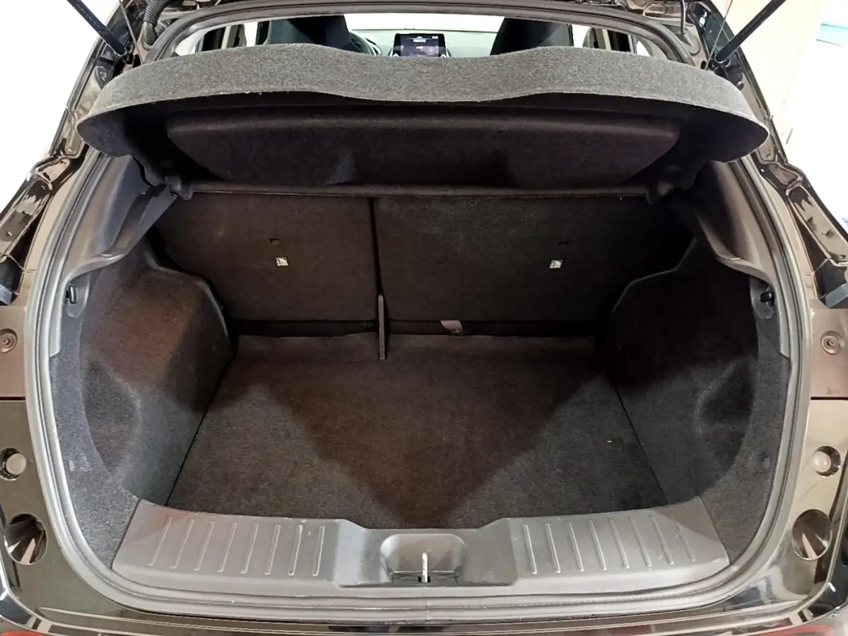 Coffre ouvert vu de l'arrière d'un Nissan Juke noir 2023, montrant l'espace de chargement et la tablette cache-bagages.