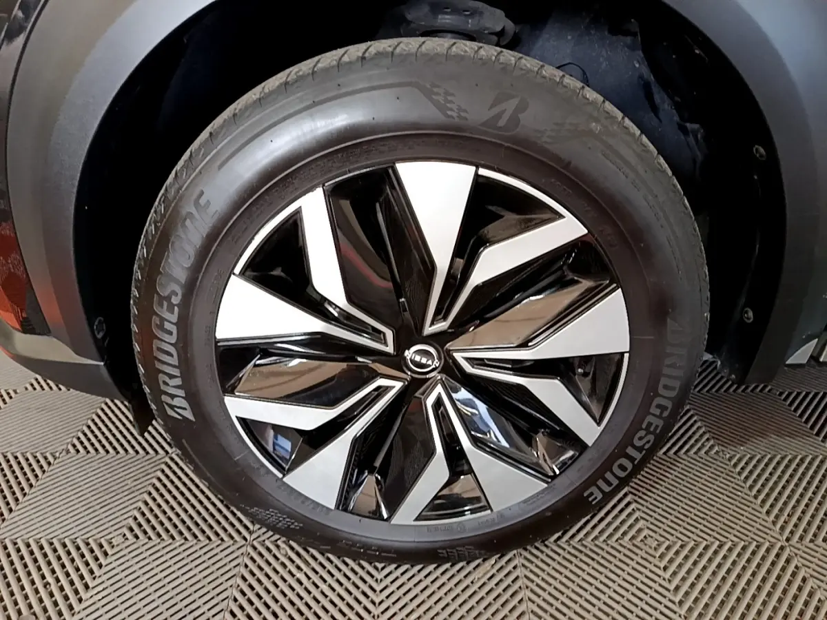 Gros plan sur la jante noire et argentée du Nissan Juke 2023 avec pneu Bridgestone, partie avant droite visible.