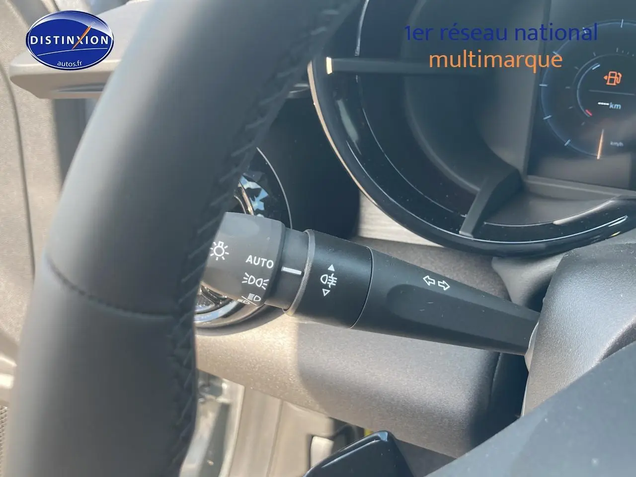Gros plan sur la manette de clignotants et phares à gauche du volant dans l’habitacle gris d’une Alfa Romeo Junior 1.2 hybride.