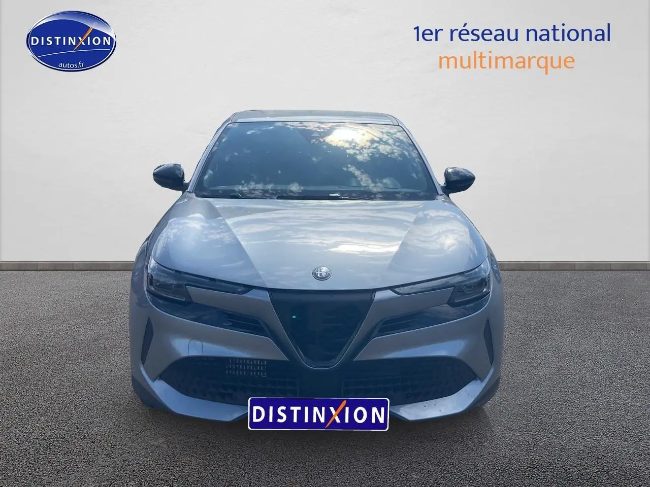 Vue avant d'une Alfa Romeo Junior 1.2 hybride gris métallisé avec calandre caractéristique et phares LED fins.