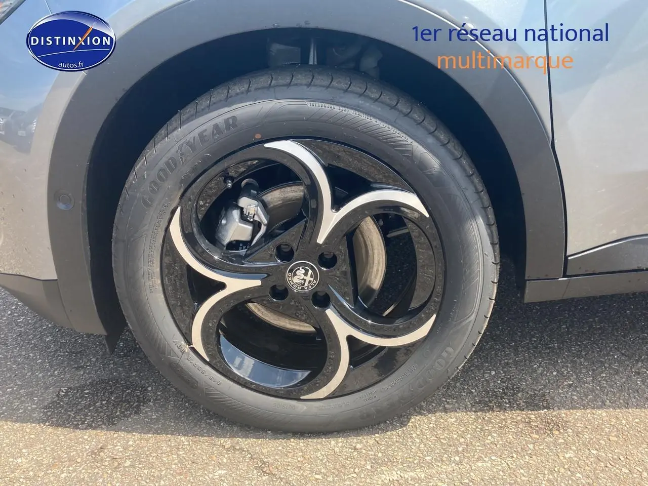 Gros plan sur la jante en alliage noire et argentée de l'Alfa Romeo Junior gris, côté arrière droit.