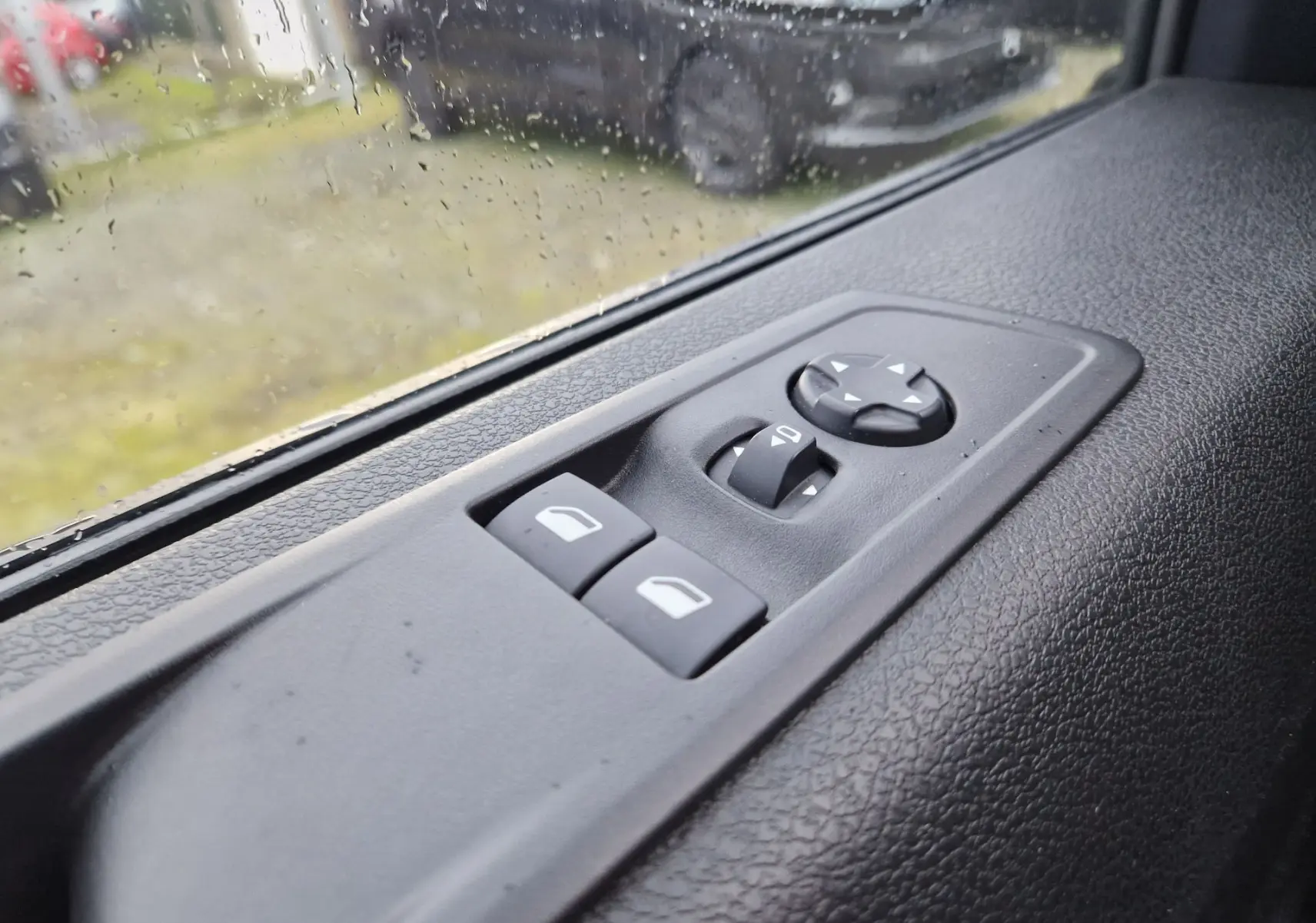 Détail des commandes de réglage des rétroviseurs et vitres sur la porte côté conducteur du Fiat Scudo Fourgon blanc 2024.