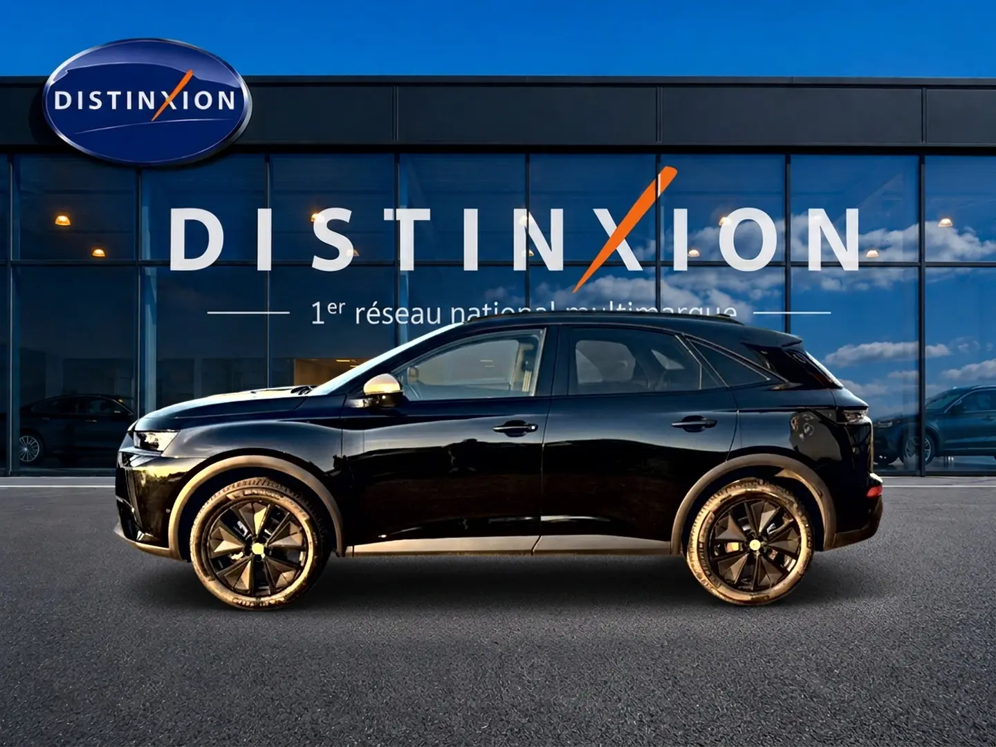 Vue latérale droite d'un DS7 noir 2026 garé devant une vitrine avec logo Distinxion en arrière-plan.