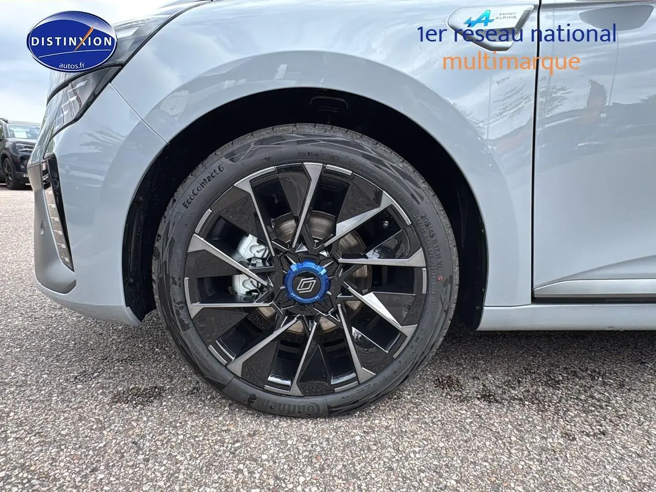 Gros plan sur la roue avant gauche de la Renault Clio V gris rafale avec jante alu 17 esprit alpine noire et bleue.