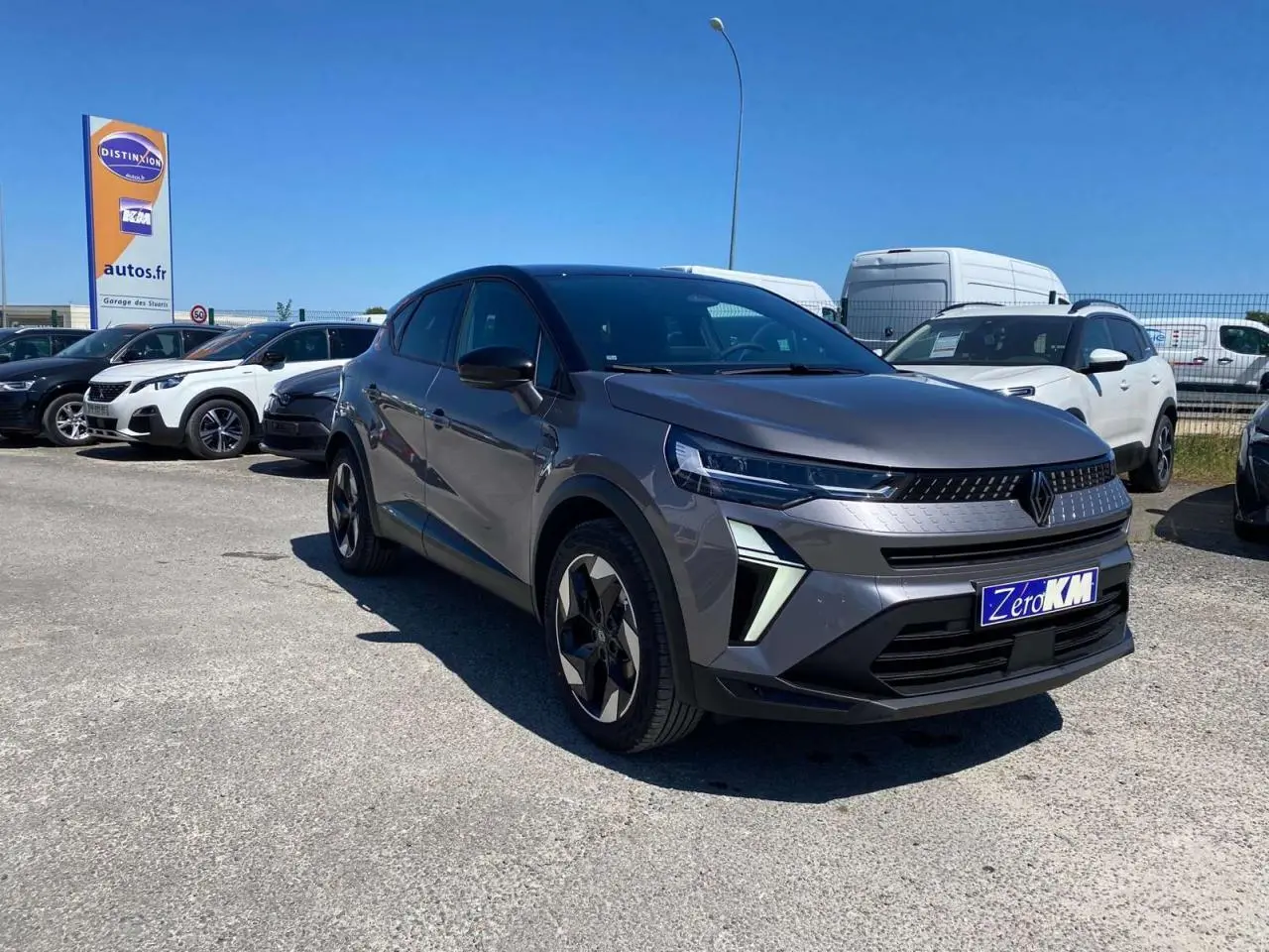 Renault Captur 2025 gris Cassiopée toit noir en 3/4 avant droit sur parking avec plaque Zero KM visible