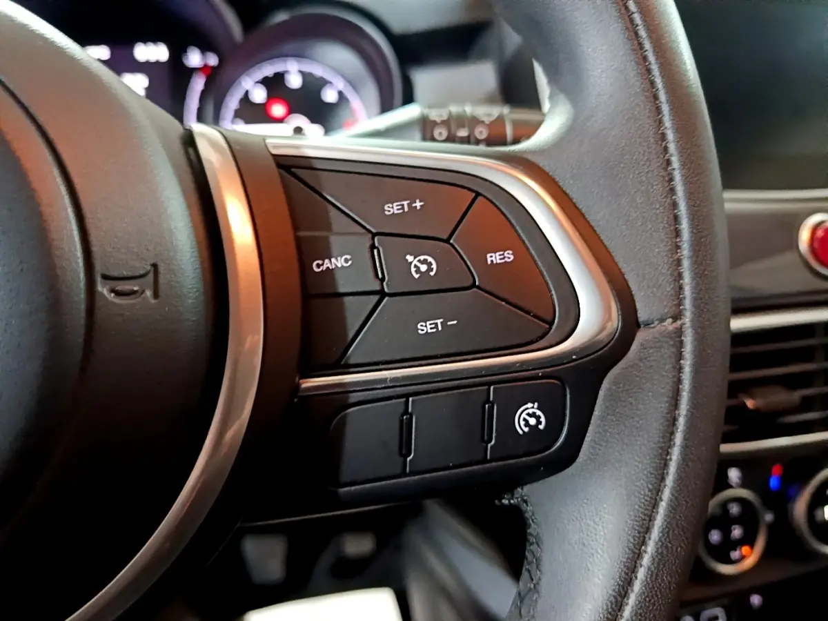 Gros plan sur la partie droite du volant noir du Fiat 500X 2019, avec commandes du régulateur de vitesse visibles.