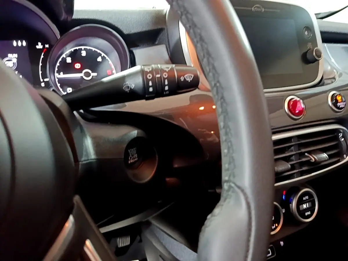 Vue intérieure rapprochée du tableau de bord et volant du Fiat 500X gris foncé, avec écran tactile et commandes visibles.