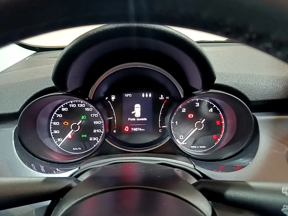 Vue rapprochée du tableau de bord de la Fiat 500X gris foncé, affichant les compteurs et l'écran central numérique.