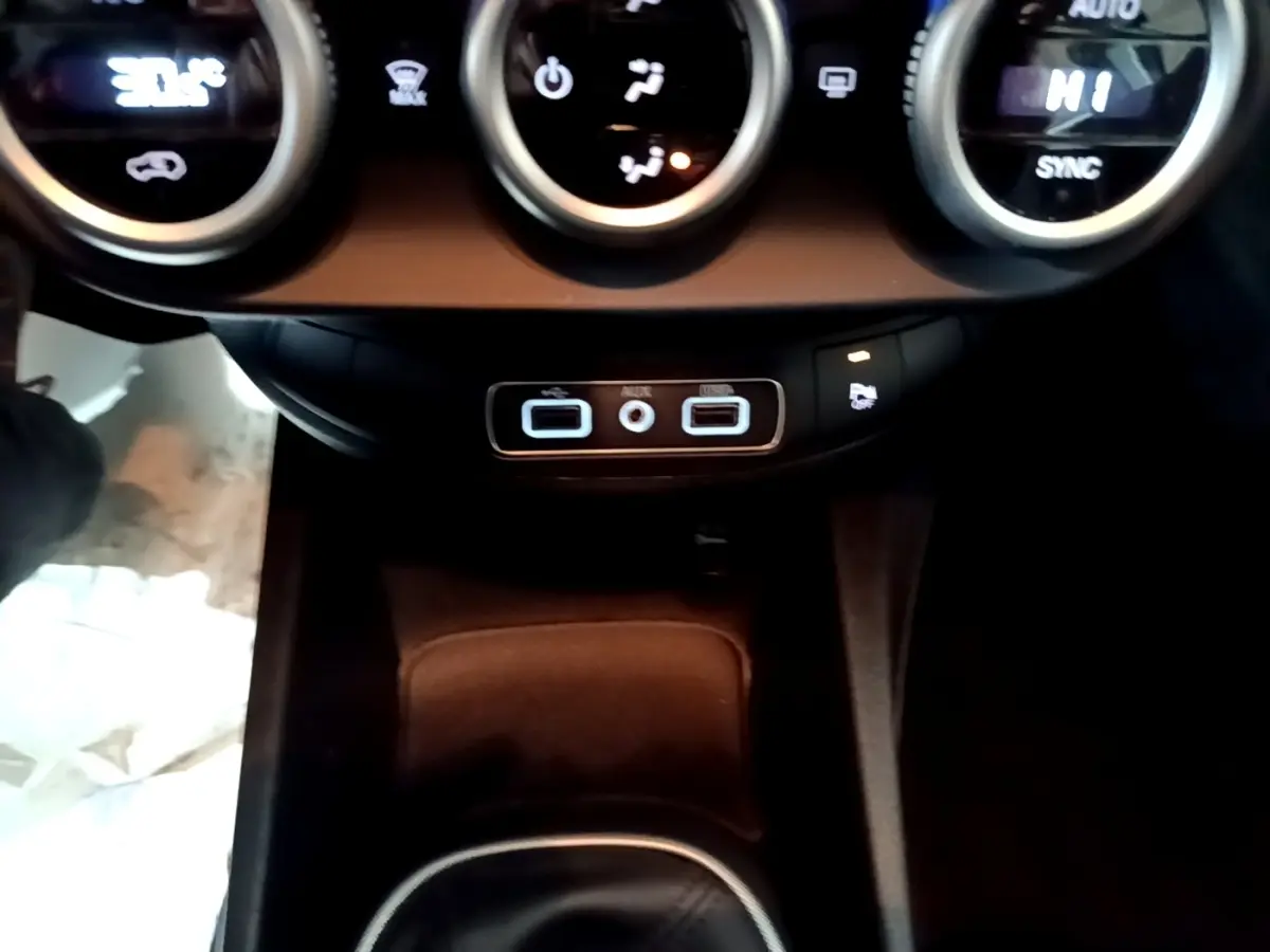 Vue rapprochée du tableau de bord et des commandes de climatisation du Fiat 500X gris foncé, avec ports USB et auxiliaire visibles.