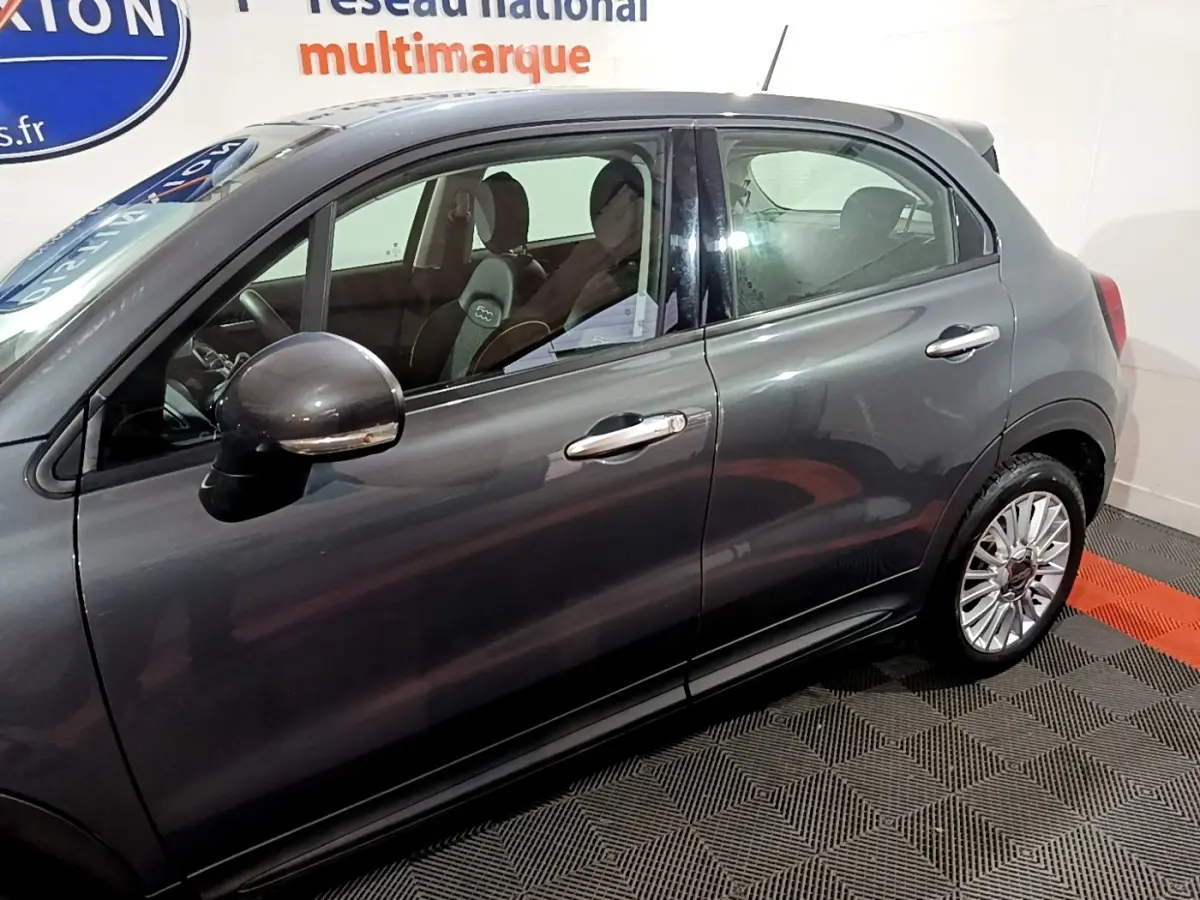 Profil droit de la FIAT 500X gris foncé, mettant en valeur les poignées chromées et les jantes alliage multibranches.