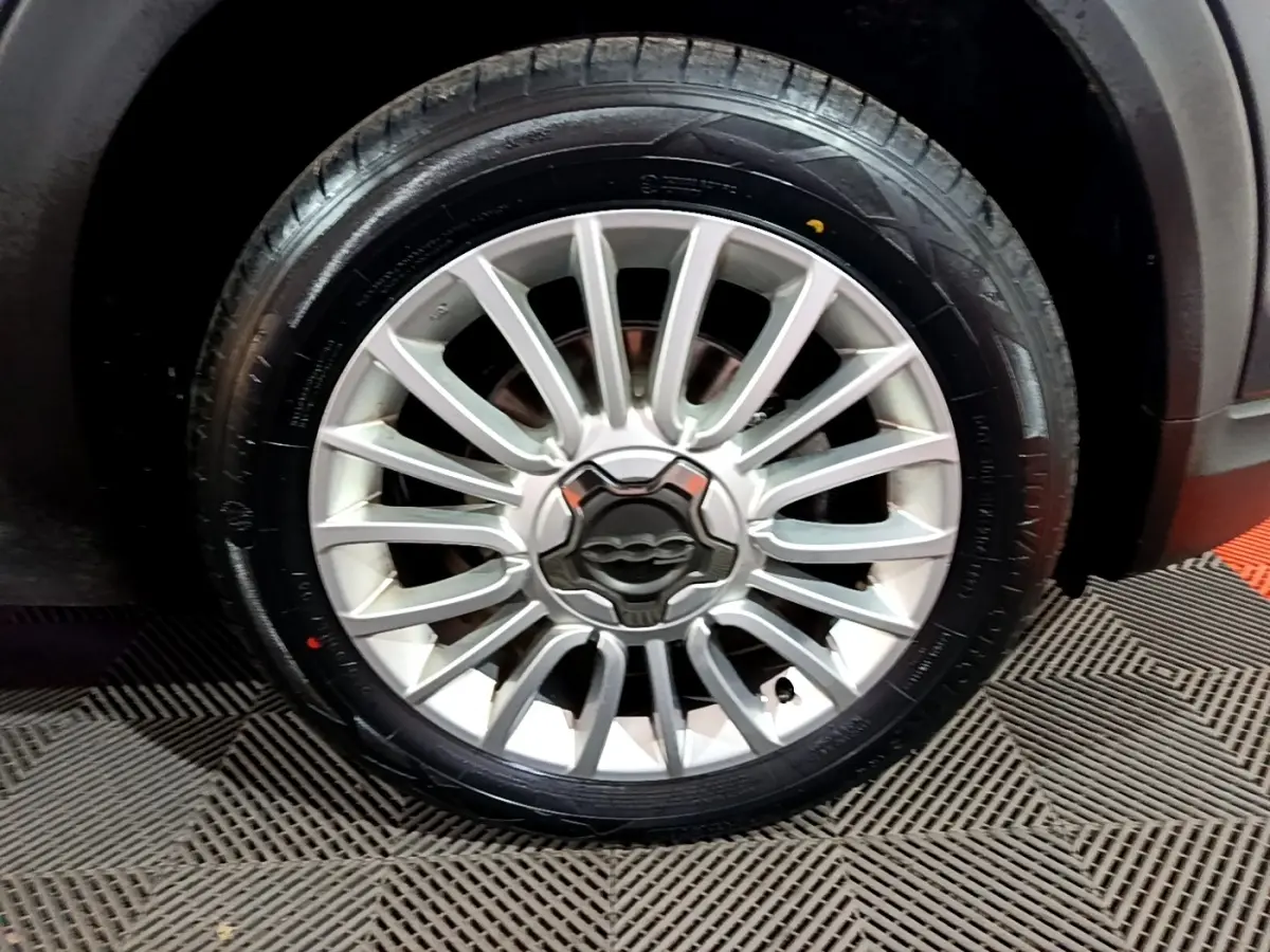 Gros plan sur la roue avant droite avec jante alliage argentée du FIAT 500X gris foncé City Cross 2019.