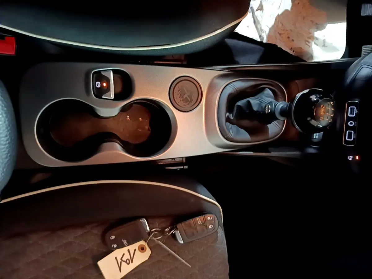 Vue plongeante sur la console centrale de la Fiat 500X gris foncé, avec levier de vitesses manuel et porte-gobelets.