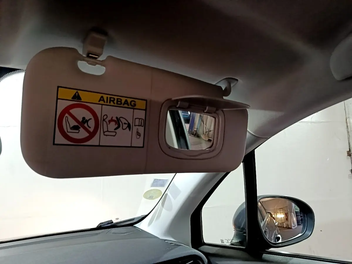 Détail intérieur du pare-soleil côté conducteur avec miroir et avertissement airbag dans une Fiat 500X gris foncé.