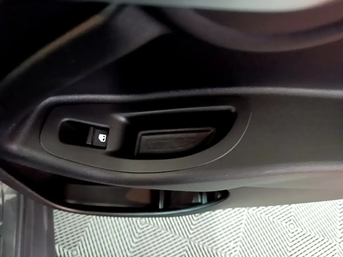 Gros plan sur la poignée intérieure et le bouton de verrouillage de la porte côté conducteur d'une FIAT 500X gris foncé.