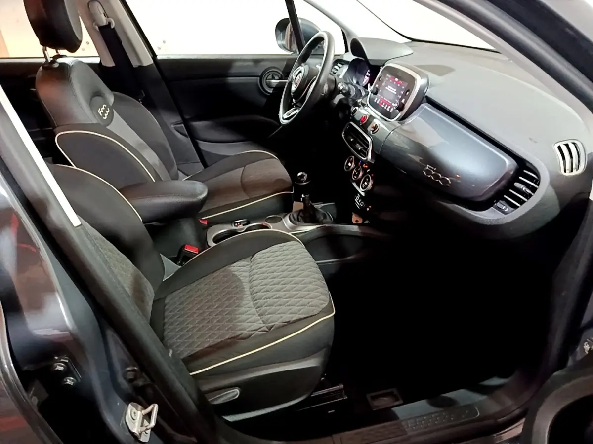 Vue intérieure côté conducteur du Fiat 500X gris foncé, mettant en valeur les sièges noirs et le tableau de bord avec écran tactile.