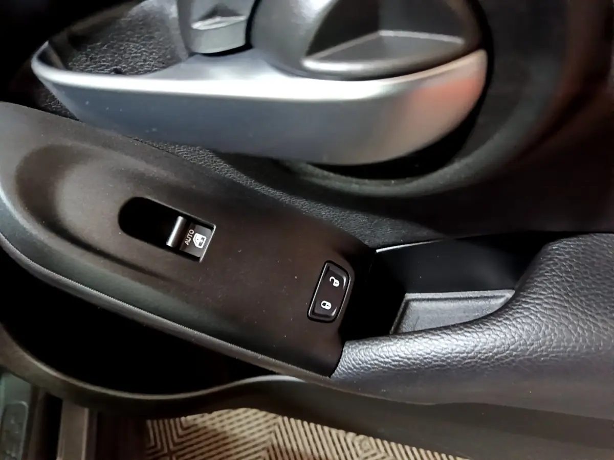 Gros plan sur la poignée de porte intérieure et les commandes de verrouillage de la FIAT 500X gris foncé côté conducteur.