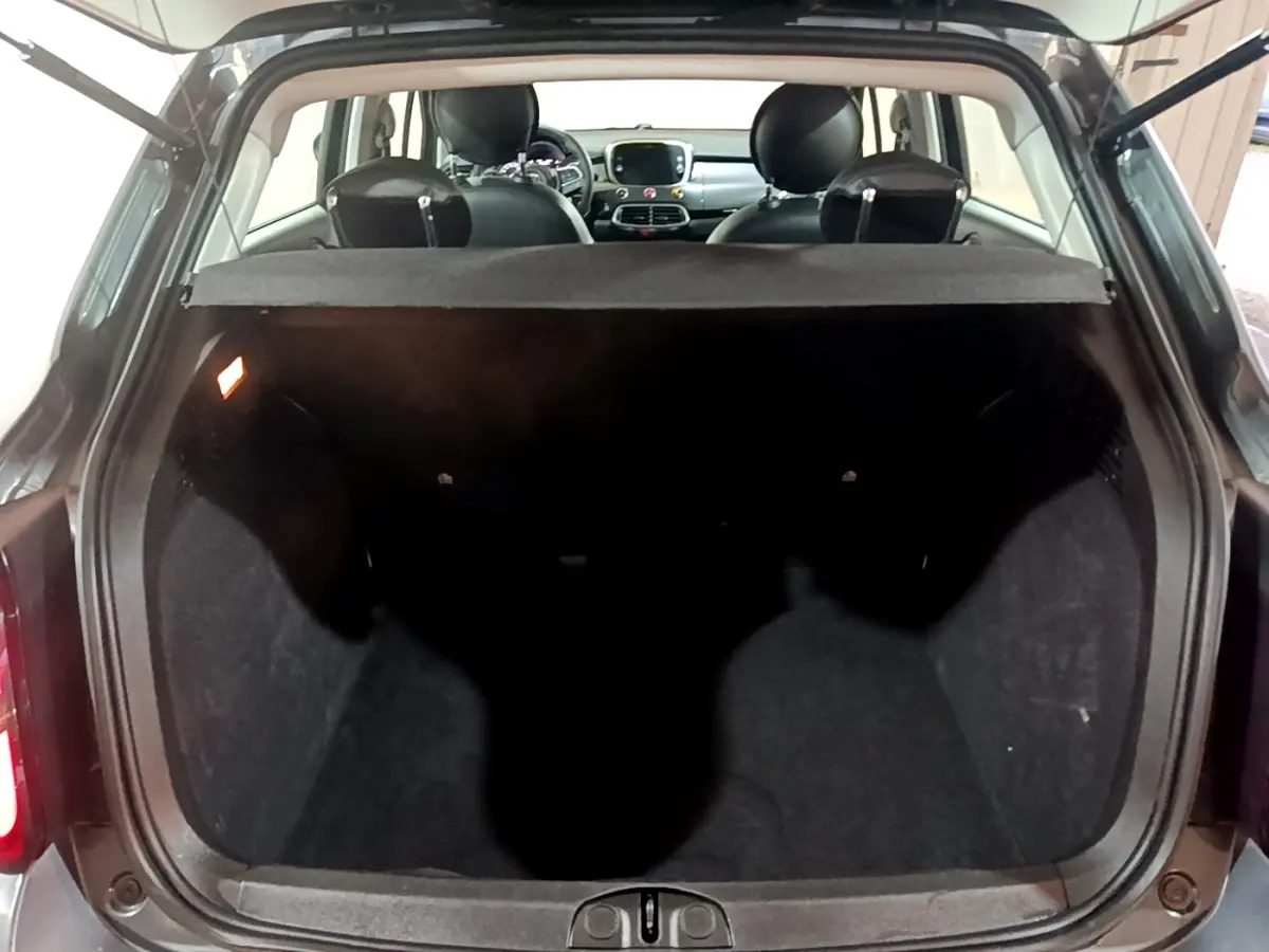 Coffre ouvert d'une FIAT 500X gris foncé vue arrière, montrant l'habitacle et la tablette cache-bagages.