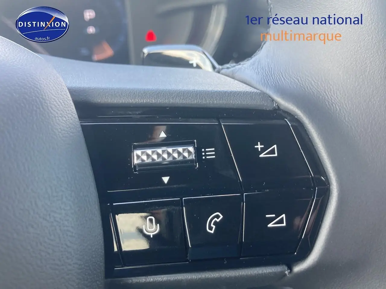 Gros plan sur les commandes au volant noir de l'Alfa Romeo Junior 1.2 hybride, avec boutons de volume et appels.