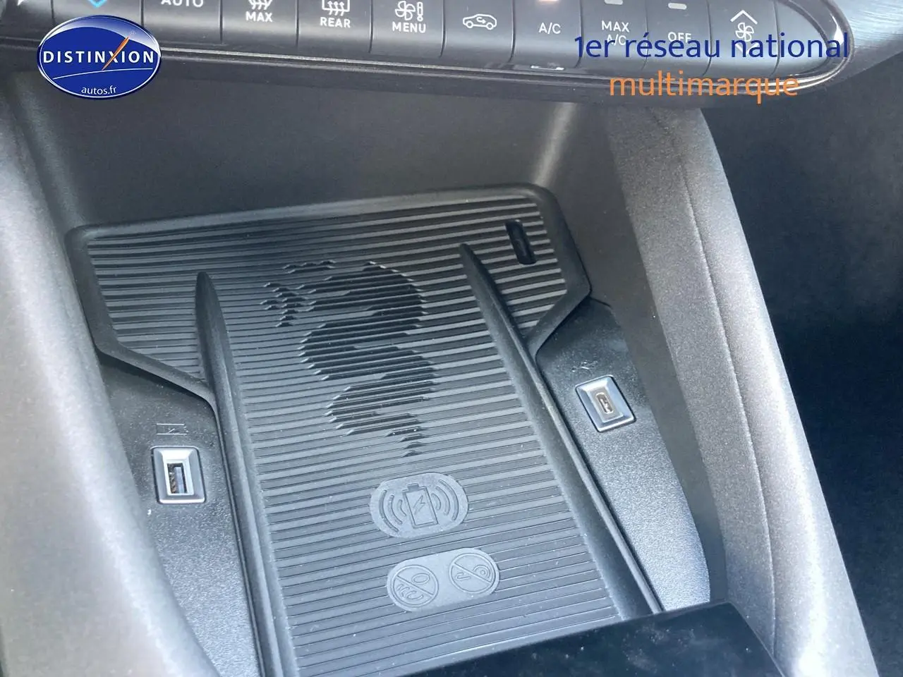 Détail du chargeur à induction avec logo serpent Alfa Romeo, entouré de ports USB dans l'habitacle noir.
