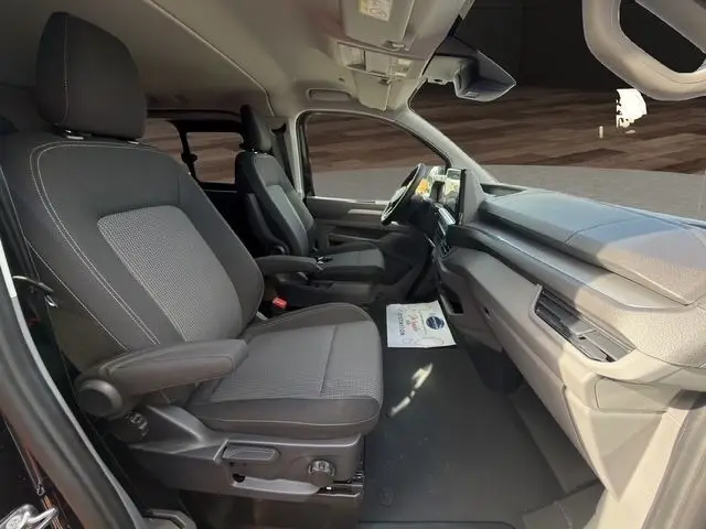 Vue intérieure côté droit du Volkswagen Transporter noir 2026, montrant les sièges avant et le tableau de bord moderne avec écran tactile.