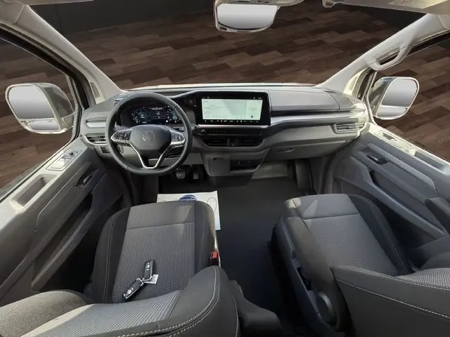 Vue intérieure avant du Volkswagen Transporter noir 2026, avec tableau de bord numérique et écran tactile central.