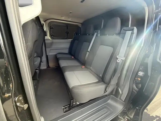 Vue intérieure côté droit du Volkswagen Transporter noir 2026, montrant la banquette arrière trois places avec ceintures de sécurité.