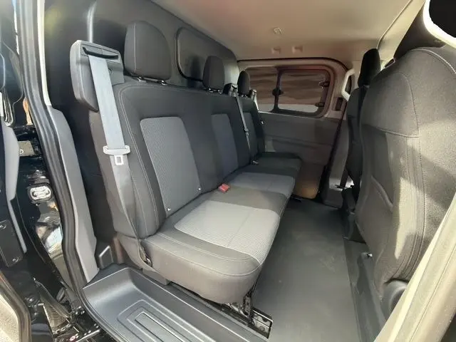 Vue intérieure côté droit des sièges arrière noirs et gris du Volkswagen Transporter 2026 avec porte coulissante ouverte.