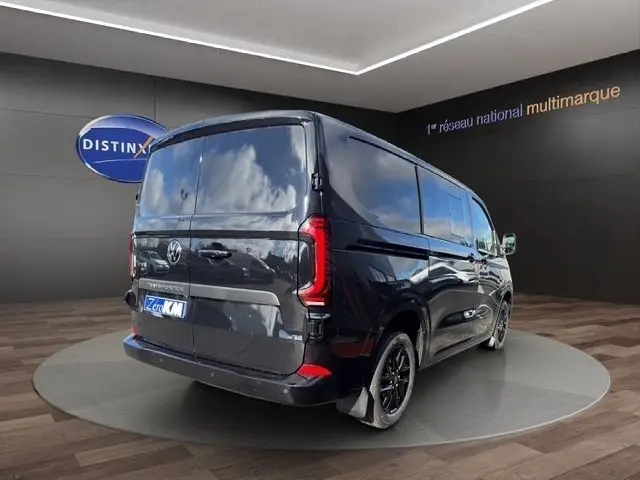 Vue 3/4 arrière droite d’un Volkswagen Transporter noir 2026 avec jantes noires et feux arrière LED distinctifs.