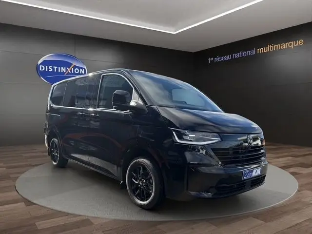 Volkswagen Transporter noir en 3/4 avant droit, avec jantes noires et phares LED, présenté en showroom.
