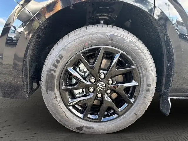 Gros plan sur la roue avant droite noire brillante du Volkswagen Transporter 2.0 TDi 170 BVA8 avec jante en alliage noir.