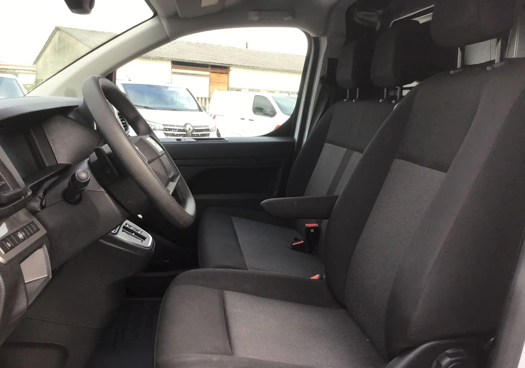 Vue intérieure côté conducteur du Fiat Scudo Fourgon 2024, sièges tissu noir et console de bord visible.