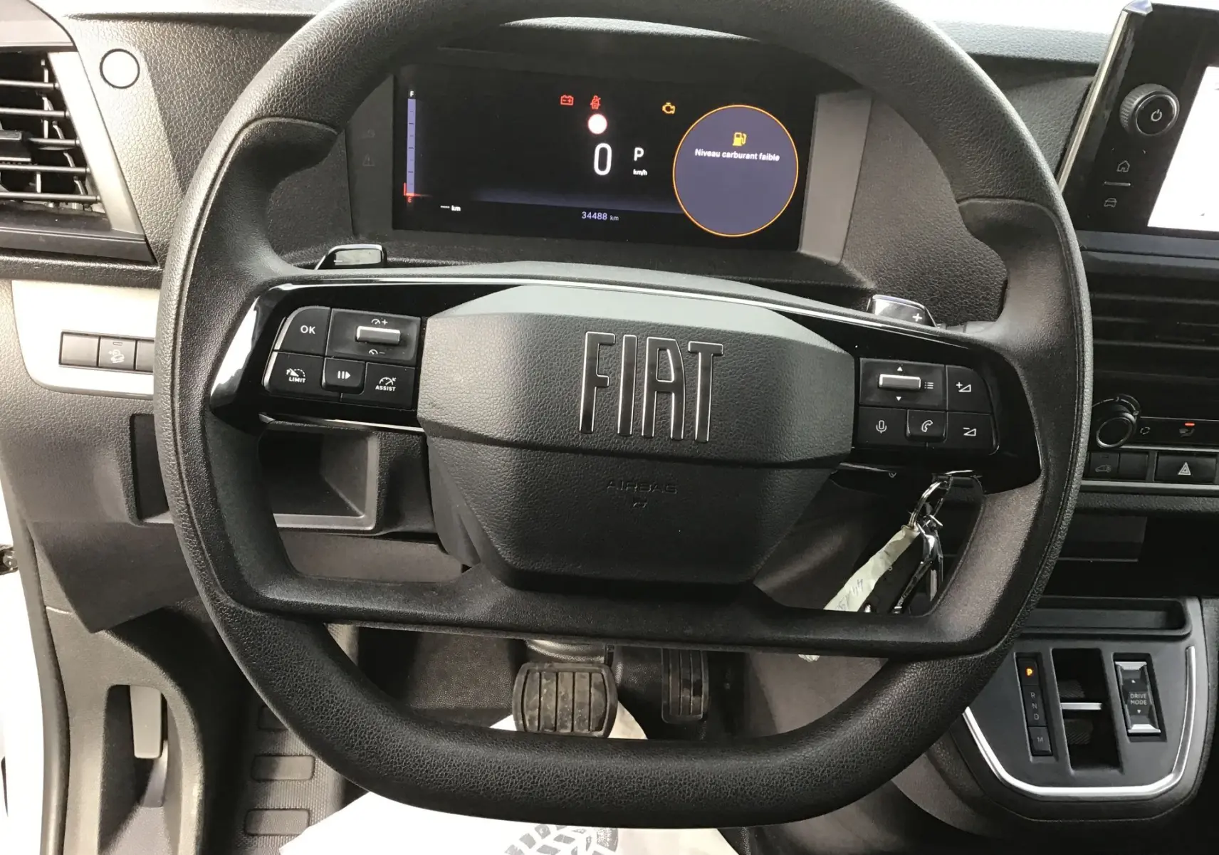 Vue rapprochée du volant noir du Fiat Scudo Fourgon 2024 avec tableau de bord numérique affichant un niveau de carburant faible.
