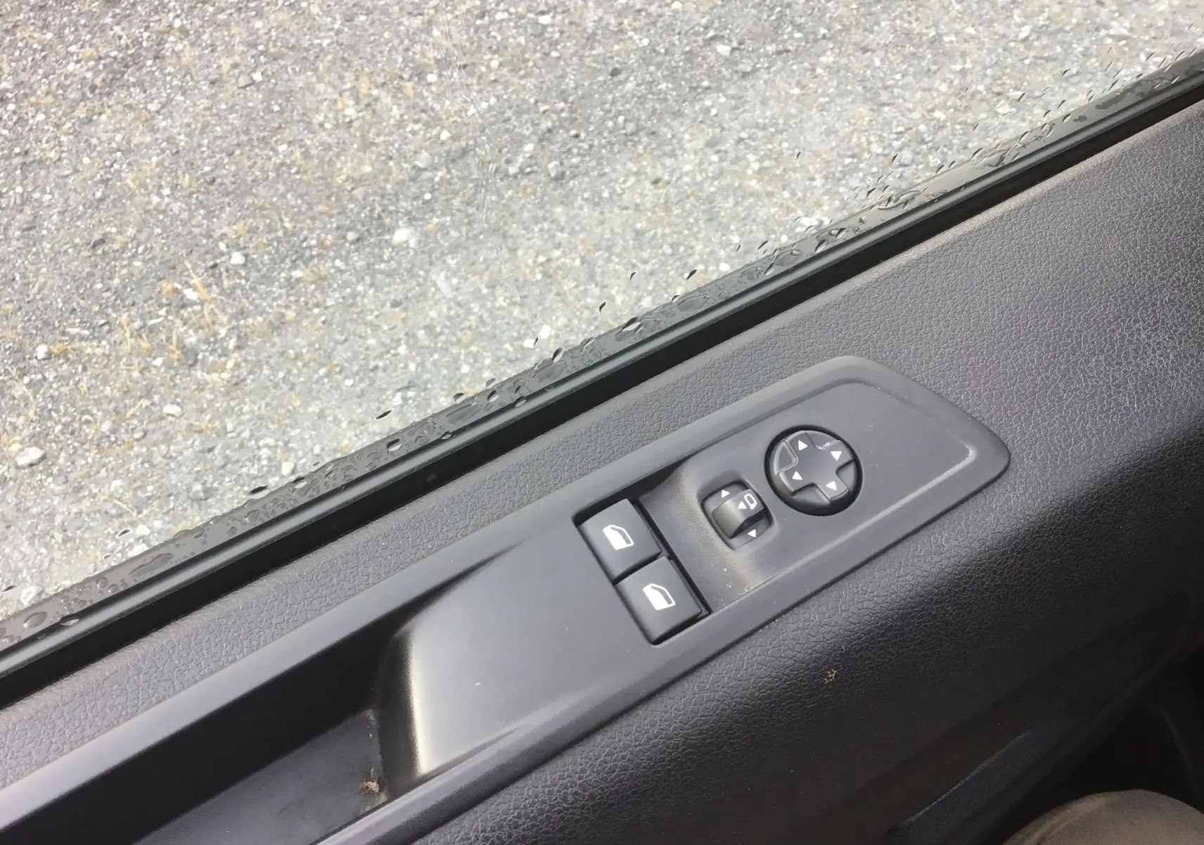 Gros plan sur les commandes de lève-vitres et réglage des rétroviseurs côté conducteur du Fiat Scudo Fourgon blanc 2024.