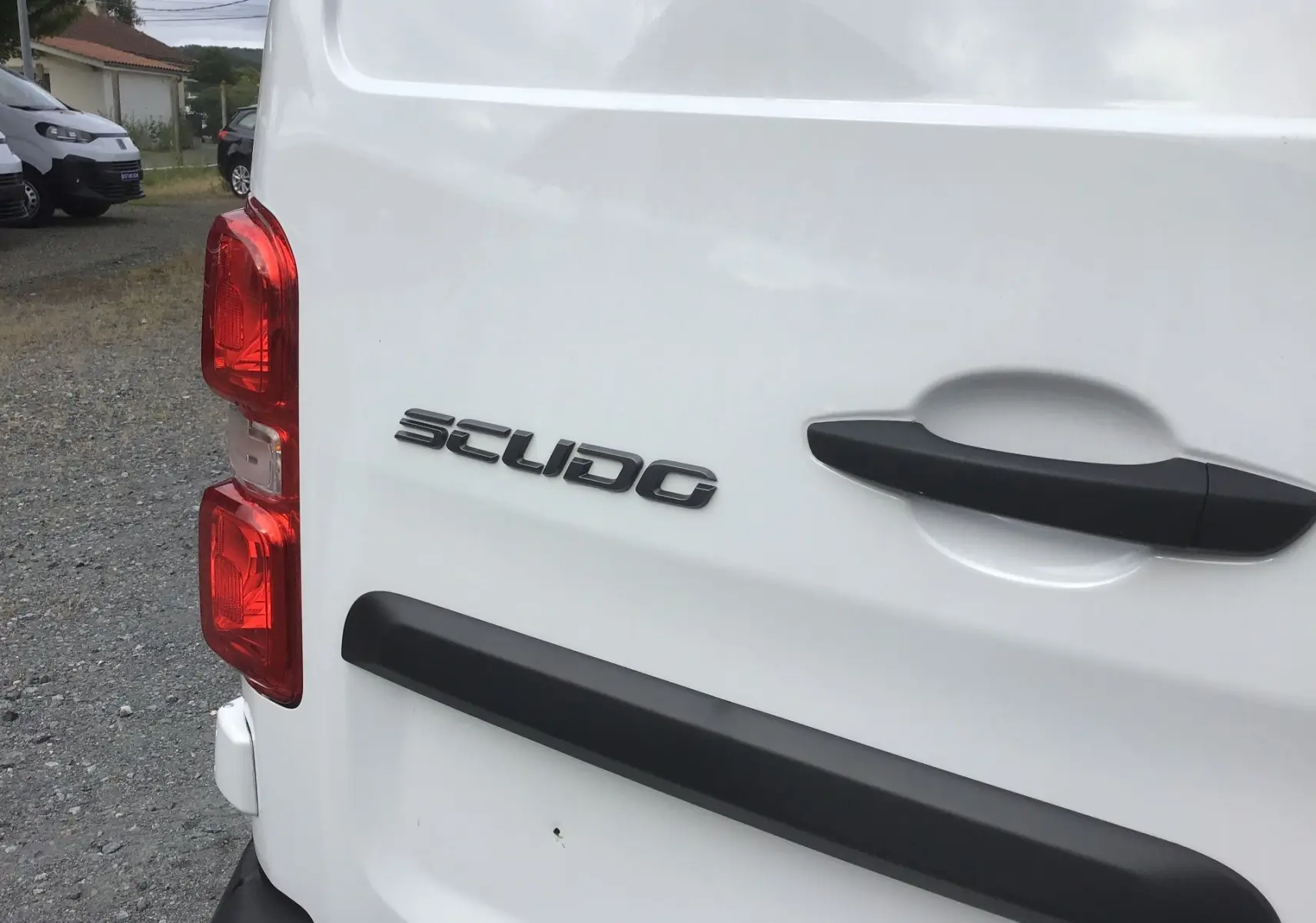 Gros plan sur l’arrière gauche blanc du FIAT Scudo Fourgon avec poignée noire et feux rouges visibles.