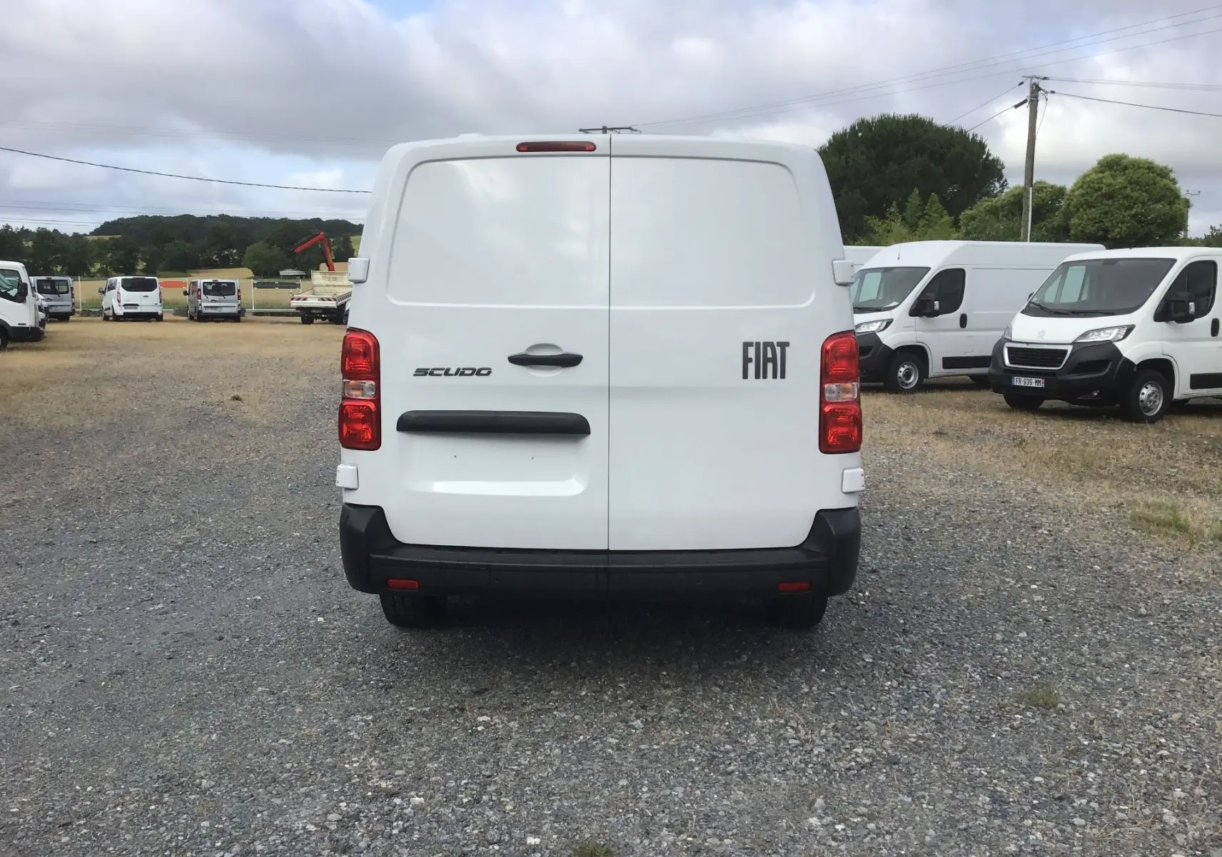Vue arrière d'un FIAT Scudo Fourgon blanc 2024, avec portes battantes et logo FIAT visible à droite.