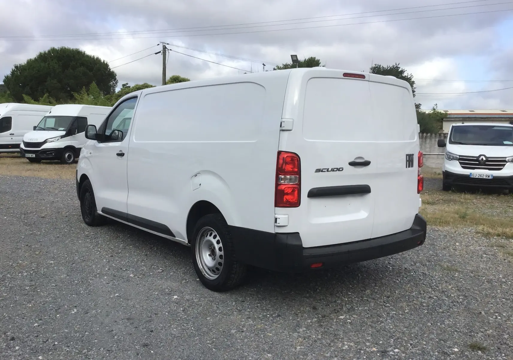 Vue 3/4 arrière droite d’un FIAT Scudo Fourgon blanc 2024 avec pare-chocs noirs et jantes acier simples.