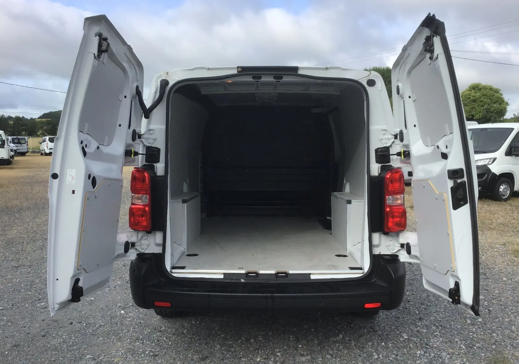 Vue arrière du FIAT Scudo Fourgon blanc 2024 avec portes arrière ouvertes montrant l’espace de chargement vide.