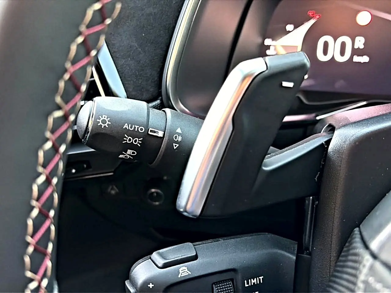 Détail du levier de vitesses automatique et commandes au volant en cuir noir avec surpiqûres rouges dans un DS7 noir.