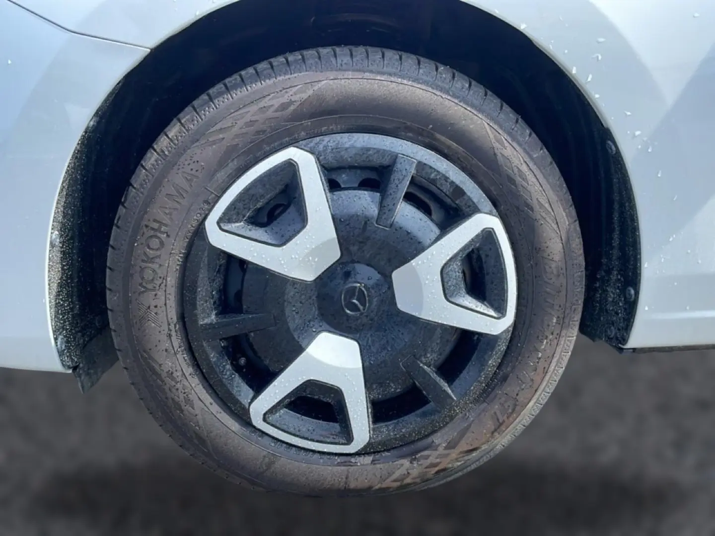 Gros plan sur la roue avant droite d’une Mazda2 blanche avec jante noire et inserts gris.