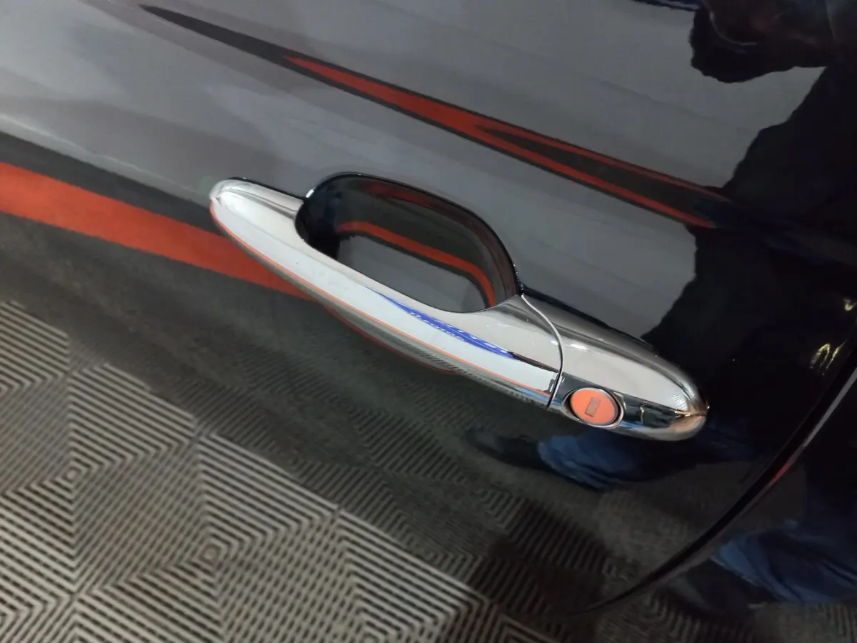 Poignée de porte chromée sur la portière noire d'une FIAT 500 1.2 8V 69ch Lounge, vue rapprochée côté droit.