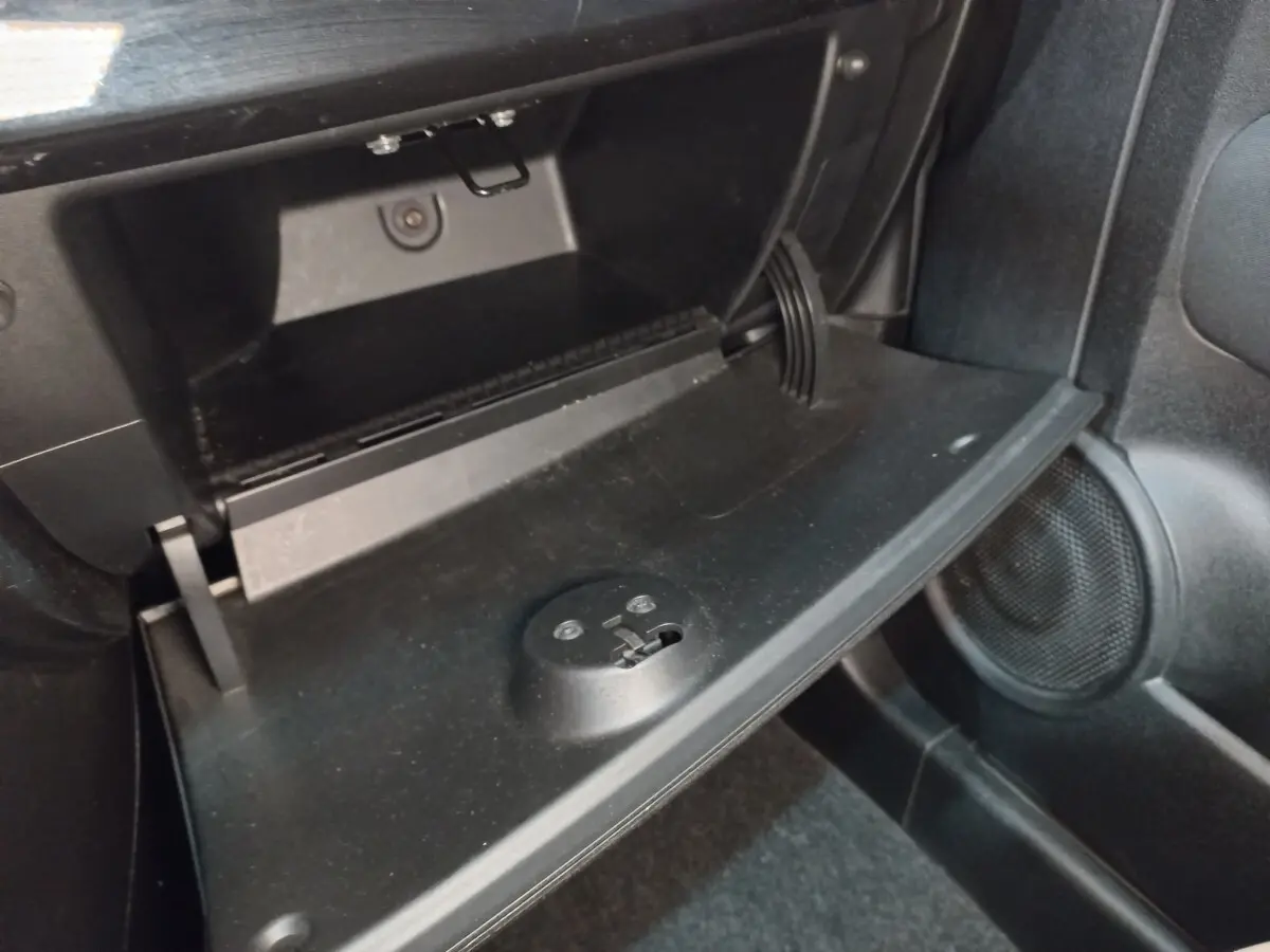 Vue rapprochée de la boîte à gants ouverte côté passager de la FIAT 500 noire, intérieur noir avec haut-parleur visible.
