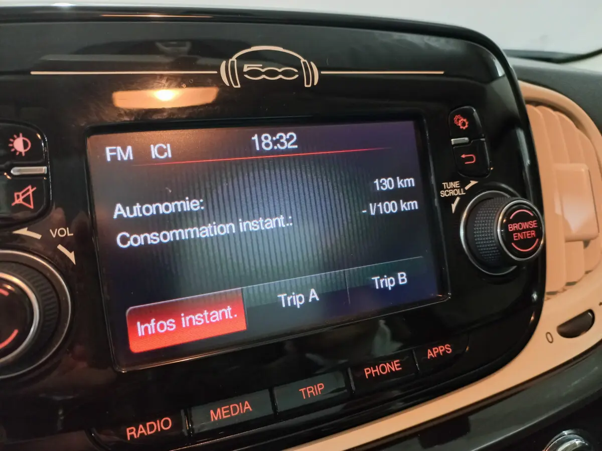 Écran tactile central noir de la Fiat 500 2018 affichant l'autonomie et les options multimédia, vue intérieure rapprochée.