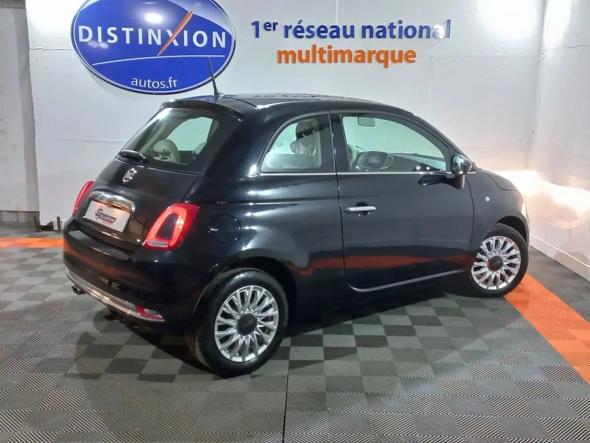 Vue 3/4 arrière droite d'une FIAT 500 noire Lounge 2018, avec feux arrière allumés et jantes argentées.