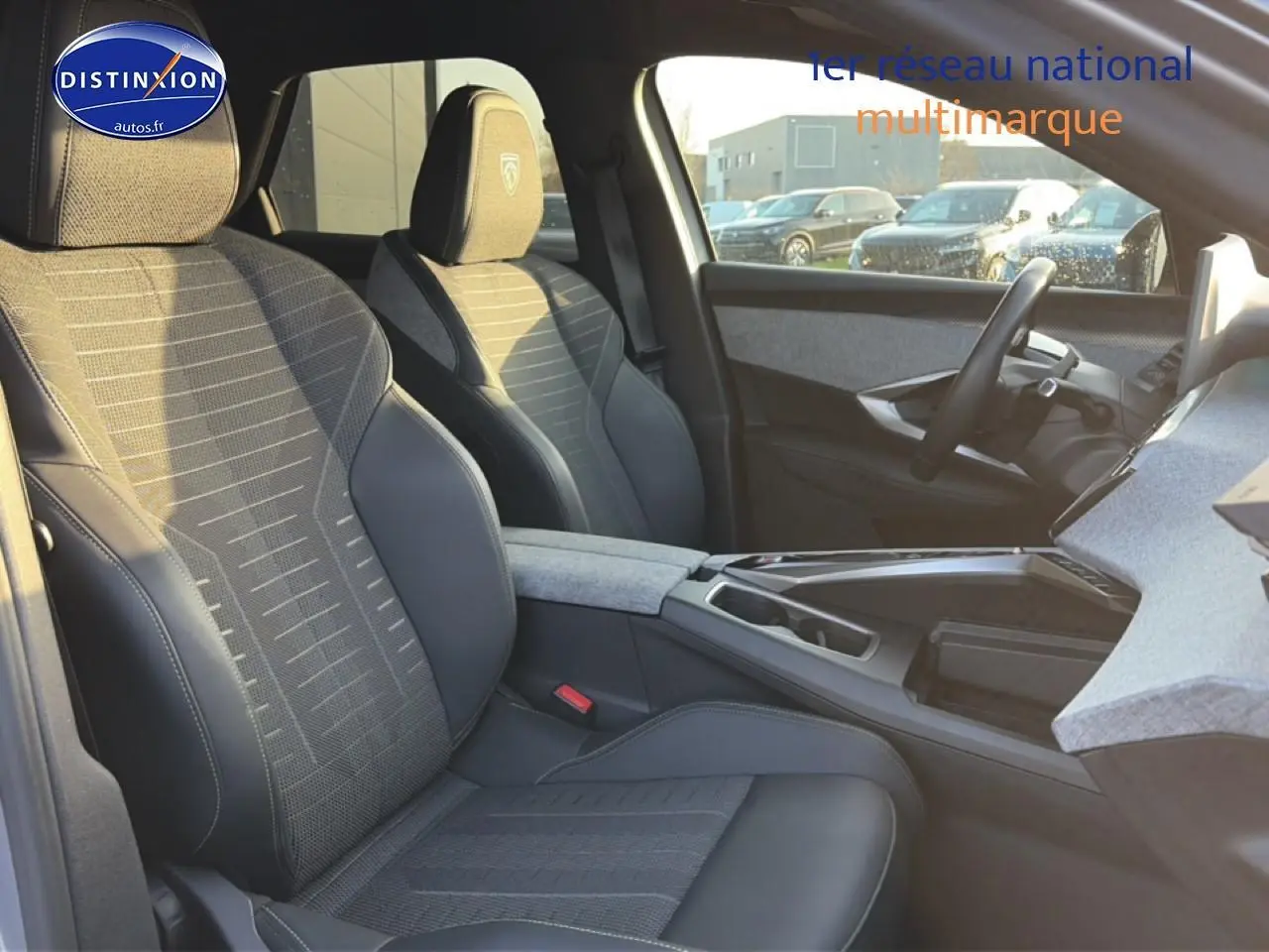 Intérieur avant droit du Peugeot 3008 gris 2025, sièges tissu et cuir avec accoudoir central et volant multifonction.