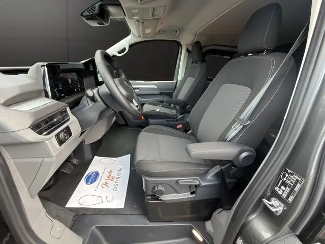 Intérieur côté conducteur du Volkswagen Transporter gris foncé 2026, avec sièges tissu gris et tableau de bord moderne.