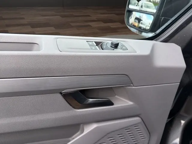 Vue rapprochée de la porte côté conducteur du Volkswagen Transporter gris foncé, avec commandes électriques des rétroviseurs.