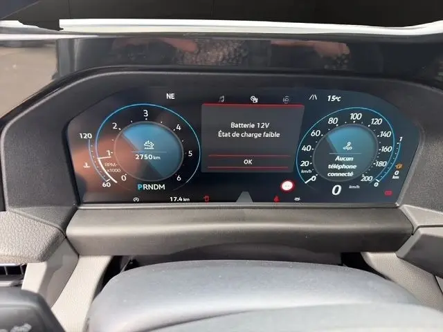 Vue rapprochée du combiné d'instruments numérique du Volkswagen Transporter gris foncé, affichant un message batterie faible.