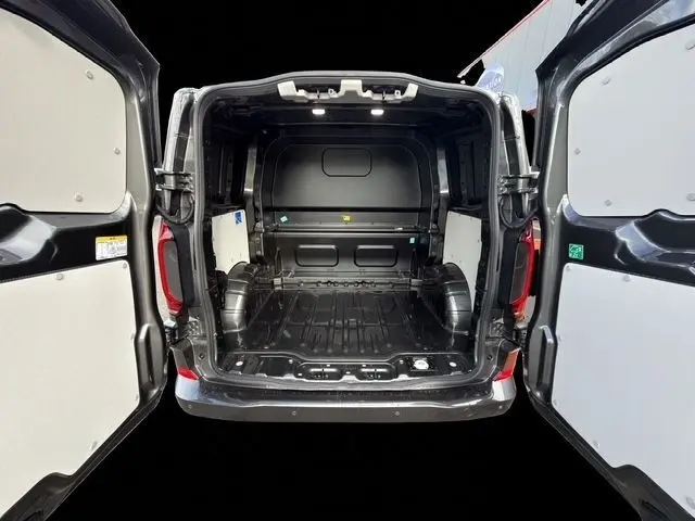 Vue arrière ouverte du Volkswagen Transporter gris foncé, montrant l’espace de chargement vide et la cloison intérieure.